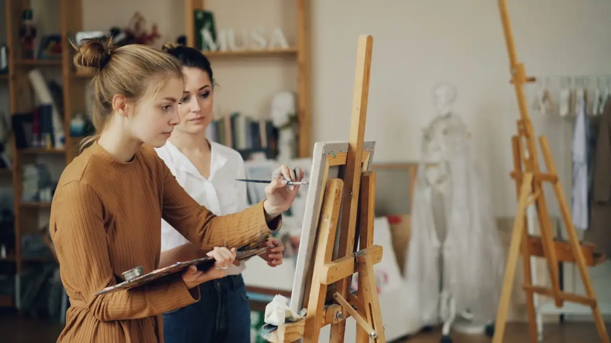 Two artists painting together in a bright, warm studio